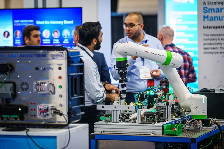 Two men talking in front of smart manufacturing equipment at a conference