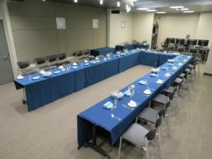 Tables with blue tableclothes set up for a dinner meeting