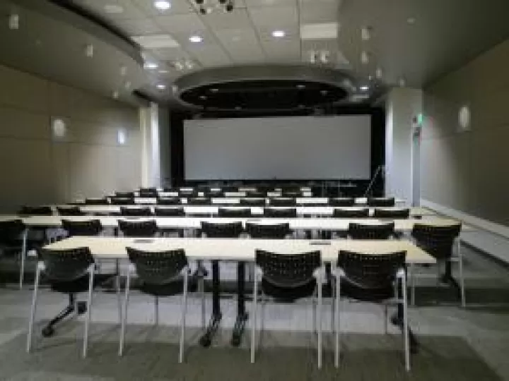 Backside view of chairs and tables facing a screen.