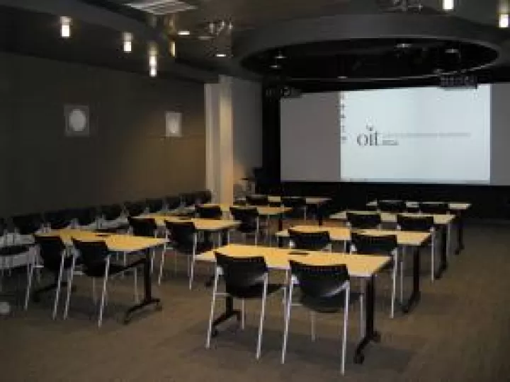 A room with chairs and tables facing a screen