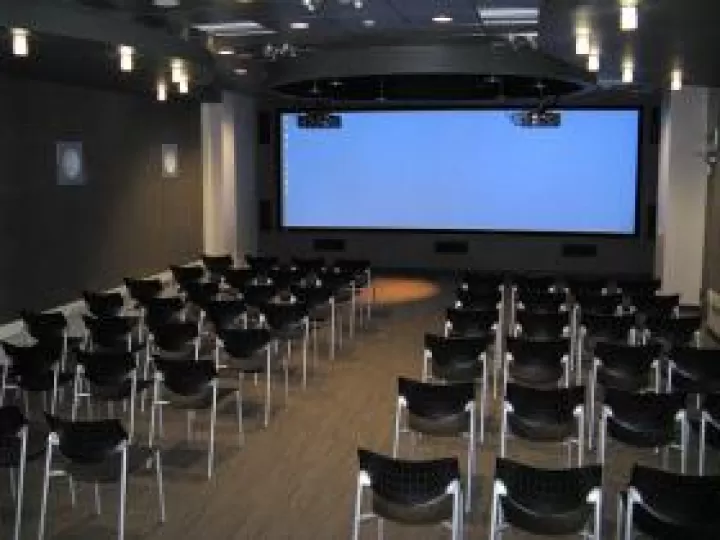 The backs of chairs arranged in rows and facing a screen