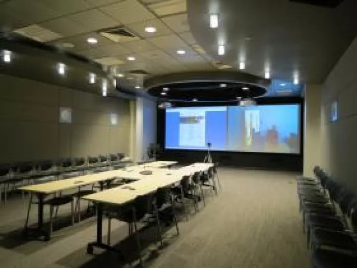 Tables pushed together with a conference phone in the middle and chairs around