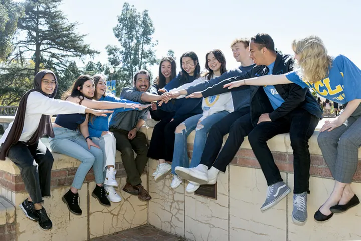 The DCP team sitting on a wall with their hands outstretched toward the middle