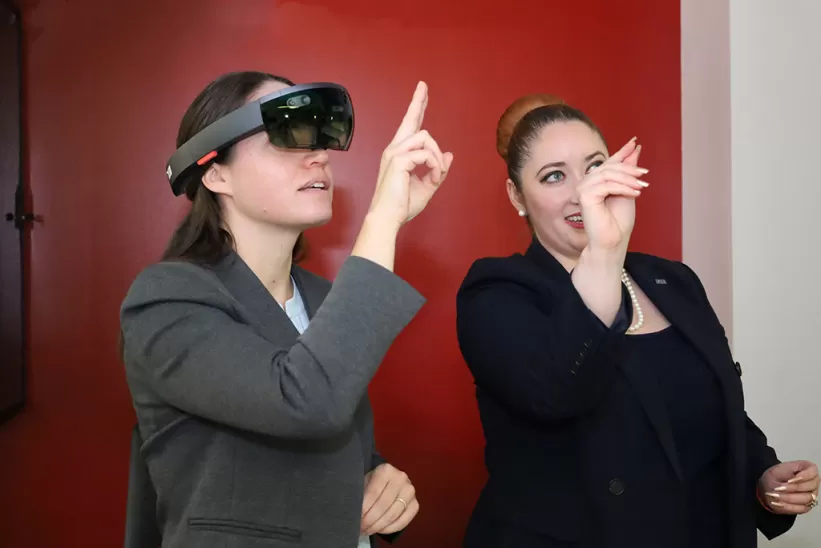 One woman showing another how to gesture in a VR headset
