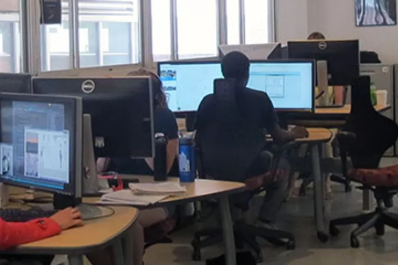 People working at computer stations inside the Sandbox Technology Lab with natural light.